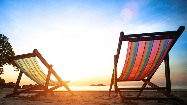 Betriebsferien Zwei Strandstühle am Meer mit Sonnenuntergang